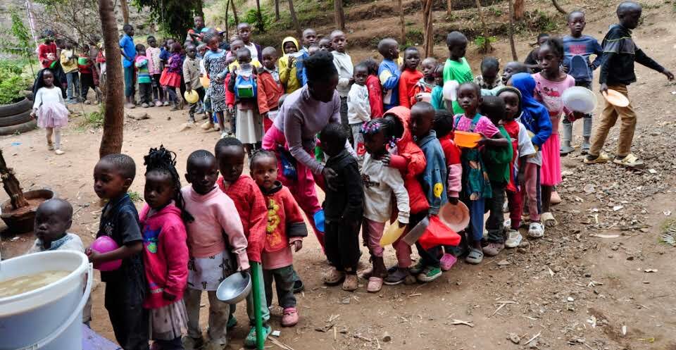 A long line of children waiting with bowls during MaSCA's feeding program