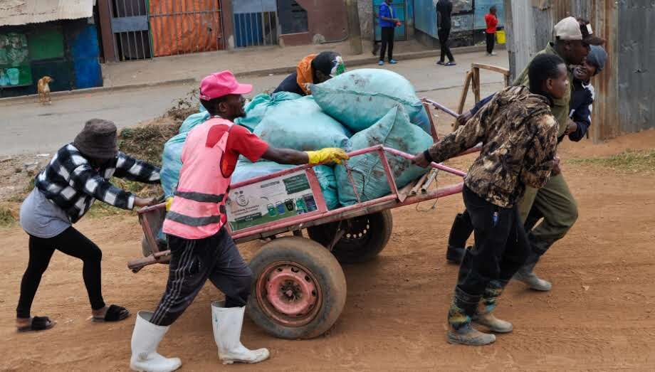 GreenPekee team pushing a loaded handcart through Mathare on a waste collection route