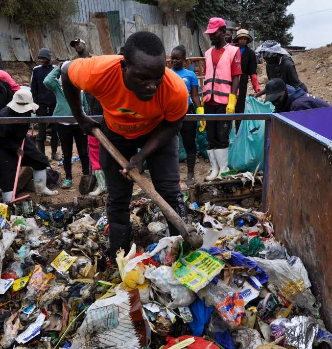 A GreenPekee worker shoveling sorted waste into a collection bin