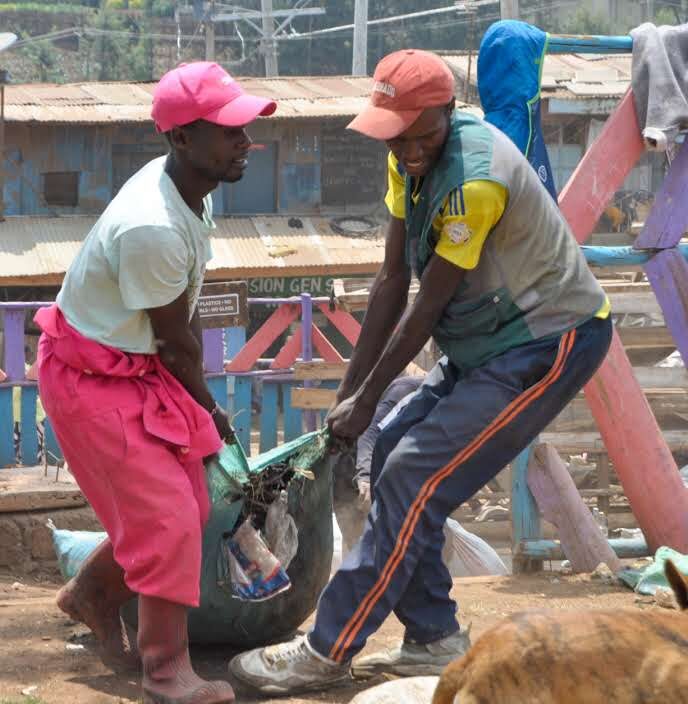 Two GreenPekee workers lifting a full sack during a Zero Waste collection drive